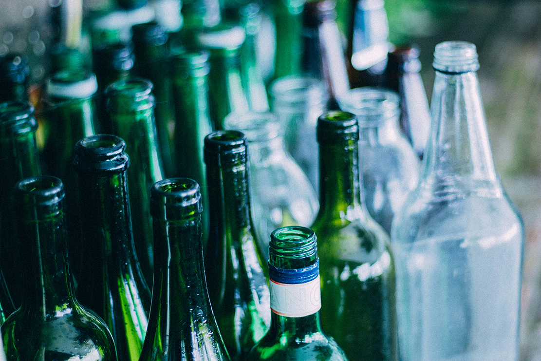 Grüne und weiße Glasflaschen stehen in eine Haufen nebeneinander